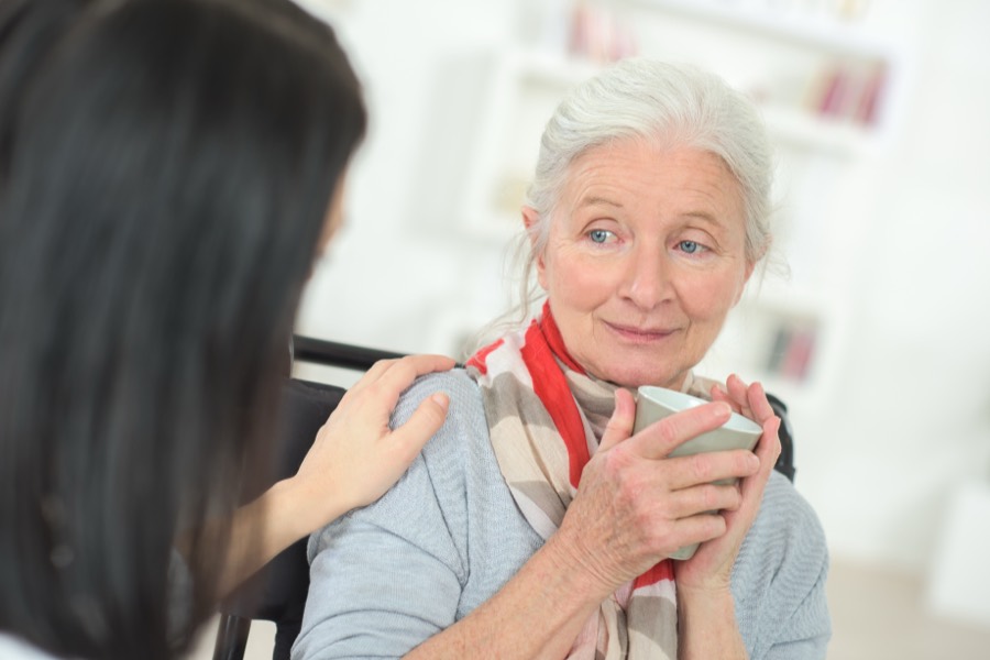 A caregiver reassuring a smiling older woman